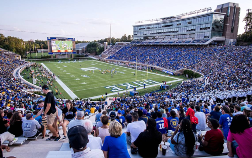 A wide view of the Brooks Field Football Stadium at Duke University with fans filling the bleachers onlooking the field and videoboard.